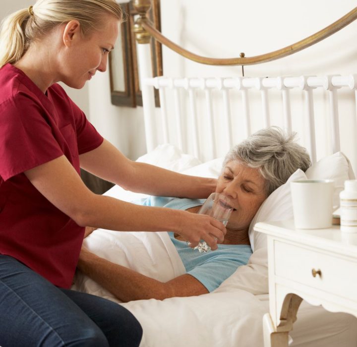 Health care worker helping patient with water