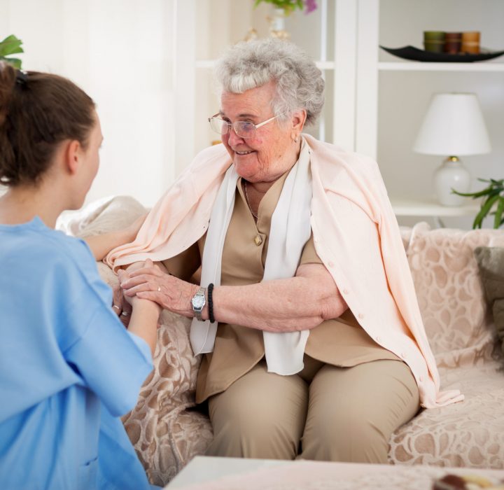 Senior person on their couch with caregiver smiling